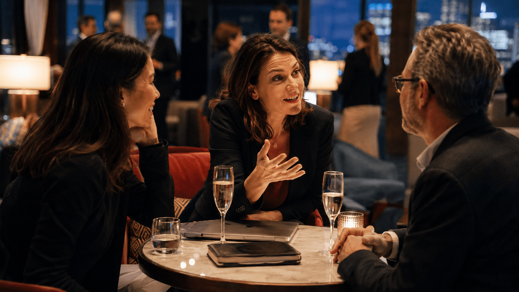 Three mid-career professionals discuss new opportunities over notebooks and champagne at an evening industry gathering